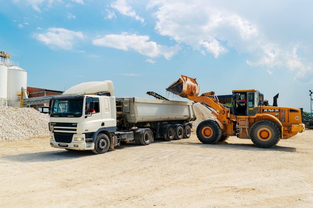 Brown Loader Beside White Cargo Truck